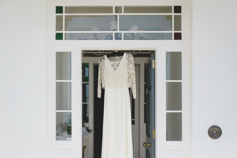 The Brides dress hanging in a doorway at a wedding in Jersey, Channel Islands