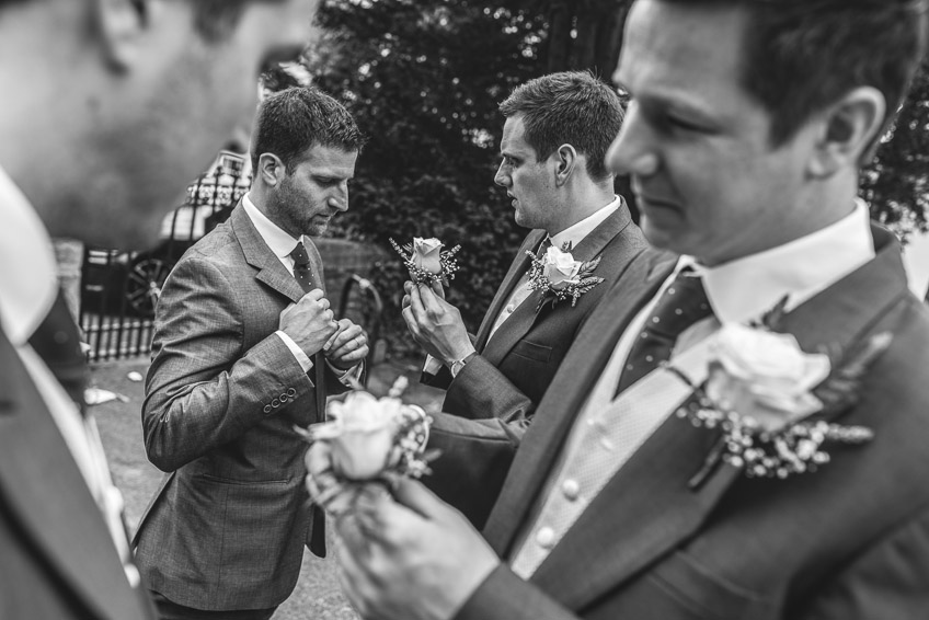 groomsmen pinning their buttonhole flowers