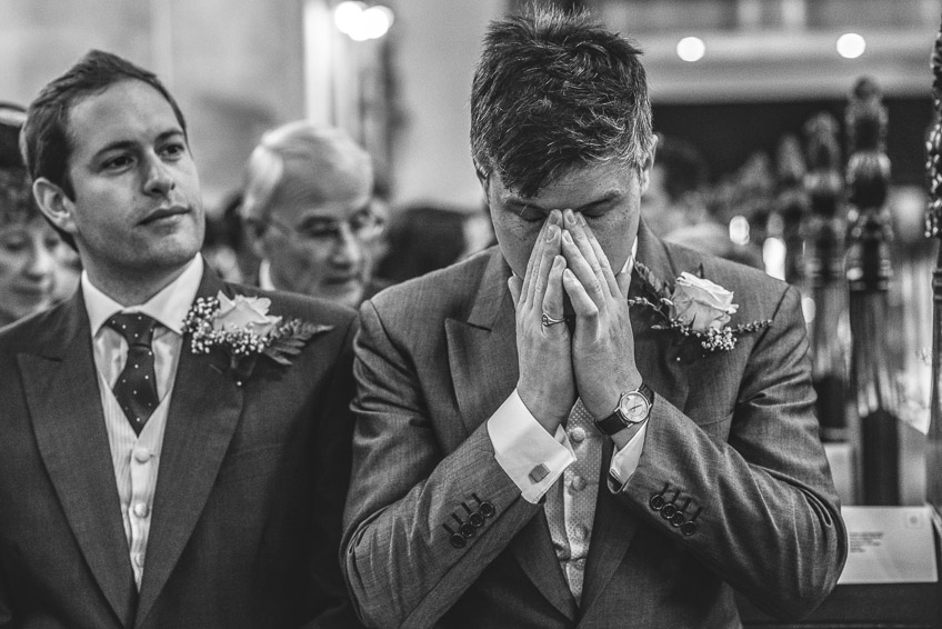 groom holding hands to face during ceremony