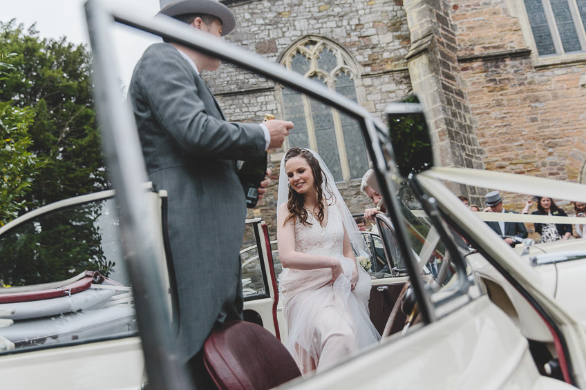 bride stepping into wedding car