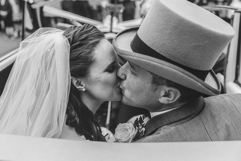 bride and groom kissing in car