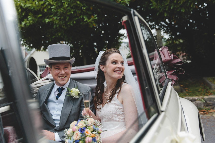 bride and groom smiling in car